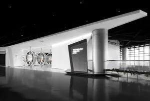 Modern minimalist exhibition space with white walls, polished concrete floors, large circular illuminated display structures, and a floating Technology Pavilion sign.