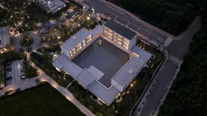 Aerial night view of a modern U-shaped concrete villa with a large central courtyard, surrounded by landscaped grounds and roads.