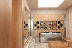 Modern music room with light birch plywood walls, built-in speakers, record collection, and a curved stainless steel console in the center.