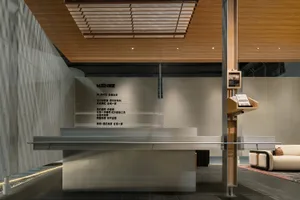 Modern minimalist reception desk made of concrete with a wooden slat ceiling and branded wall in the background.