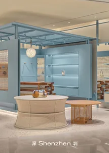 Modern retail boutique interior featuring a large circular woven rattan counter, sky-blue walls, wooden display blocks, and a spherical woven pendant light in Shenzhen.