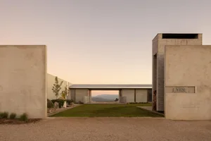 Modern concrete courtyard house named Eyrie with a perfectly manicured lawn, minimalist walls, and a mountain view at sunset.
