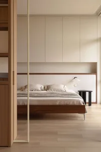 Modern minimalist bedroom with walnut platform bed, ribbed fabric headboard, built-in beige cabinetry, and black side table with wall lamp.