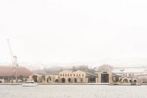 基隆港濱水歷史砂岩工業倉庫群的霧景，前景有一艘白色遊艇，左側可見施工吊車。