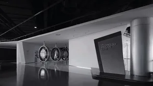 Modern minimalist exhibition space with white walls, polished dark floor, three circular suspended technology pods, and a sign for Technology Pavilion.