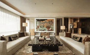Elegant luxury living room with two beige sofas facing each other, a large black marble coffee table with gold inlay, and a colorful traditional Chinese landscape painting on the back wall.