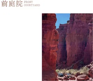 兩輛越野車停在沙漠峽谷中高聳的紅色砂岩峭壁底部。
