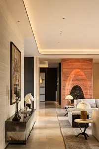 Modern luxury living room hallway featuring a dark marble console table, horse head sculpture, framed artwork, and a striking red onyx feature wall in the background with white sofas.