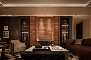 Luxurious living room featuring a curved, backlit onyx marble feature wall, dark wood cabinetry, contemporary furniture, and black and white checkered carpet.