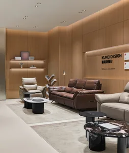 Modern luxury living room display with brown leather sofa, cream leather armchairs, black marble coffee tables, and warm wood panel walls with integrated lighting.