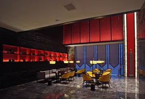 Luxury hotel lobby lounge featuring black marble walls with glowing red backlit shelves, bold red vertical slat feature wall, polished marble floor, and golden yellow velvet armchairs arranged in intimate seating groups.