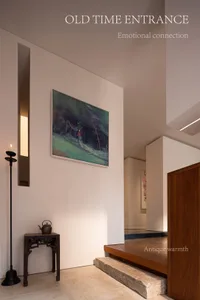 Modern minimalist entrance hall featuring a dark wooden antique Chinese console table, a tall black candle holder with lit candle, a large landscape oil painting, and warm walnut wood architectural details with stone steps.