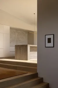 Modern minimalist split-level staircase with travertine marble wall, warm wood treads, and integrated lighting.
