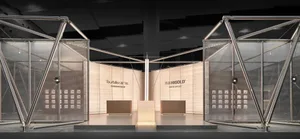 Modern exhibition booth featuring large triangular stainless steel frames, sheer mesh screens, and illuminated central display platforms with brand signage for Higold and Tourbillon.