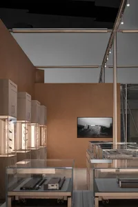 Modern jewelry store interior with oak veneer walls, illuminated glass display cases, and a black and white architectural photograph on the back wall.