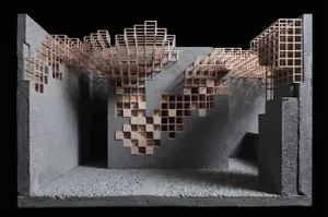 Architectural scale model of a modern library interior featuring grey concrete walls and an intricate system of light-colored wooden bookshelves arranged in a pixelated, cascading pattern across multiple levels.