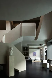 Modern minimalist living room featuring a massive sculptural concrete staircase, dark polished floors, white minimalist furniture, and abstract art in a double-height space with dramatic architectural forms.
