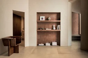 Modern minimalist entryway featuring a built-in terracotta tiled shelving unit, dark walnut sculptural console table, and neatly arranged books and ceramics.