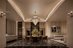 Luxurious formal dining room featuring a large sculptural chandelier, dark marble flooring with white geometric inlay, velvet dining chairs, and a prominent floral centerpiece.