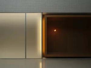 Modern minimalist interior wall with a frosted glass sliding panel on the left and an open walnut wood niche on the right containing a single glowing pendant light.