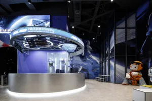 Modern circular stainless steel information counter with integrated LED lighting in a blue-themed aerospace science center exhibition space featuring astronaut murals and digital displays.