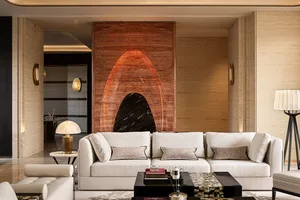 Modern luxury living room featuring a large white sectional sofa, black marble coffee table, and a dramatic two-tone marble feature wall with an arched cutout in warm brown and black onyx.