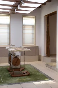 Industrial-style wooden and metal rocking horse with attached granite-topped play table on a green road-patterned rug in a bright modern room