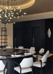 Modern luxury dining room featuring a large round black marble dining table, white upholstered dining chairs with black frames, and a dramatic sculptural chandelier with green-tinted glass orbs hanging from a curved ceiling.