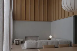 Modern minimalist living room featuring vertical wood paneling on the upper wall, a large light-grey modular sofa, a built-in concrete fireplace, and a spherical white pendant lamp.