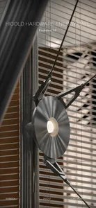 Close-up of a modern brushed metal wall sconce with a circular fluted shade and articulated mechanical arm mounted on a dark vertical surface in front of horizontal window blinds.