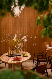 Elegant dining area featuring a large round onyx marble table, four brown leather armchairs, dramatic floral arrangement, and warm walnut wood paneling.