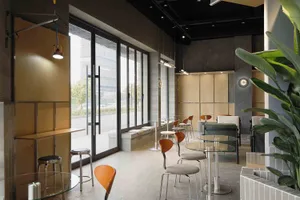 Modern industrial-style cafe interior featuring round glass tables, orange molded chairs, concrete walls, wooden accents, and large windows overlooking the street.
