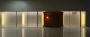 現代室內細節，展示嵌入式溫暖照明壁龕，內有一盞懸吊燈泡，周圍環繞無縫拉絲金屬櫃體並設有整合式LED燈光。
