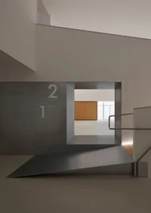 Modern minimalist concrete staircase with floating platform leading to a bright upper-level showroom with wooden cabinetry