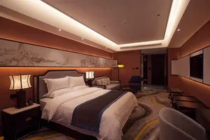 Modern luxury hotel bedroom featuring a large Chinese ink landscape painting above the bed, warm walnut furniture, layered lighting, and a patterned carpet in earth tones.