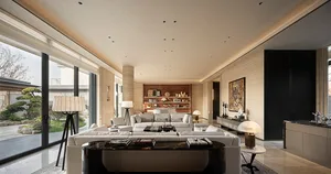 Modern luxury living room featuring light travertine walls, a large white sectional sofa, black marble coffee table, and large glass doors opening to a Japanese-style garden with bonsai trees.