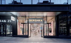 Bershka 現代服飾店夜景，大面積玻璃櫥窗內透出粉色燈光，可見服裝展示與模特兒，以及明亮的品牌招牌。