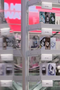 Modern retail perfume display featuring white acrylic shelves with integrated LED lighting, showcasing Grafen, Mi-a, and ahro fragrance collections against a vibrant pink neon background.