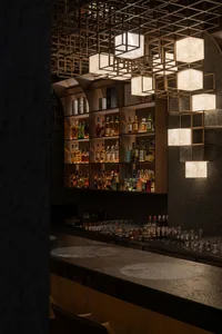 Luxurious speakeasy-style bar interior featuring a long textured plaster counter, backlit wooden shelving filled with liquor bottles, and a striking geometric brass grid ceiling with glowing fabric lanterns.