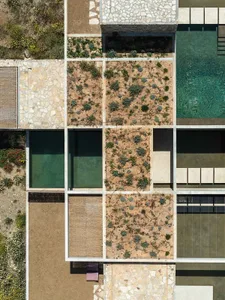 Bird's eye view of a modern villa's geometric courtyard garden with limestone pavers, gravel beds, and native Mediterranean plants arranged in a grid pattern next to a turquoise swimming pool.
