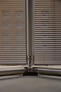 Close-up of a stainless steel T-joint connecting vertical and horizontal structural members with visible bolts and precision machining.