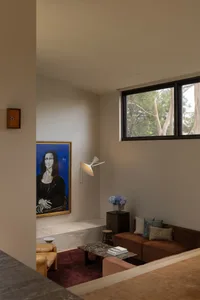 Modern living room corner with brown leather sofa, terracotta sectional, marble ledge, terrazzo coffee table, and a large framed Mona Lisa painting under warm lighting.