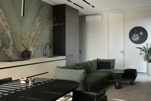 Modern living room featuring a large green marble wall, dark green L-shaped sectional sofa, black dining table, and minimalist white cabinetry.