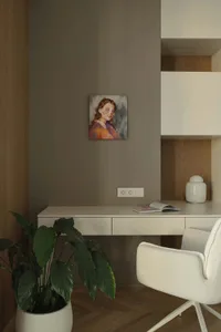 Modern minimalist home office corner with white desk, upholstered swivel chair, large potted plant, and colorful portrait painting on a taupe wall with wood paneling.
