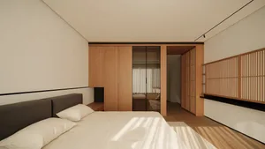 Modern minimalist bedroom featuring a low-profile bed with dark grey headboard, white bedding, built-in light oak wardrobes, and a wooden slatted decorative screen on the right wall.