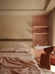 Modern bedroom featuring a beige upholstered bed with pink bedding, a terracotta sculptural armchair, and a two-tone wall with beige cabinetry and a pink fluted accent wall with floating shelves.