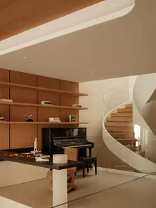 Modern interior featuring a black grand piano, built-in walnut bookshelves, a sculptural curved glass and wood staircase, and contemporary furniture under warm lighting.