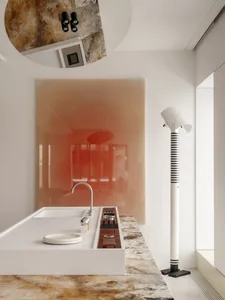 Modern minimalist kitchen with white island, chrome faucet, onyx countertop and backsplash, and a tall striped floor lamp.