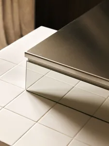 Close-up view of a modern staircase featuring white square ceramic tiles and a reflective mirrored nosing on the step edge.