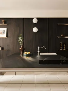Modern dark walnut kitchen island with integrated white rectangular sink, chrome bridge faucet, floating shelves, and decorative objects including a brown ceramic vase with eucalyptus.
